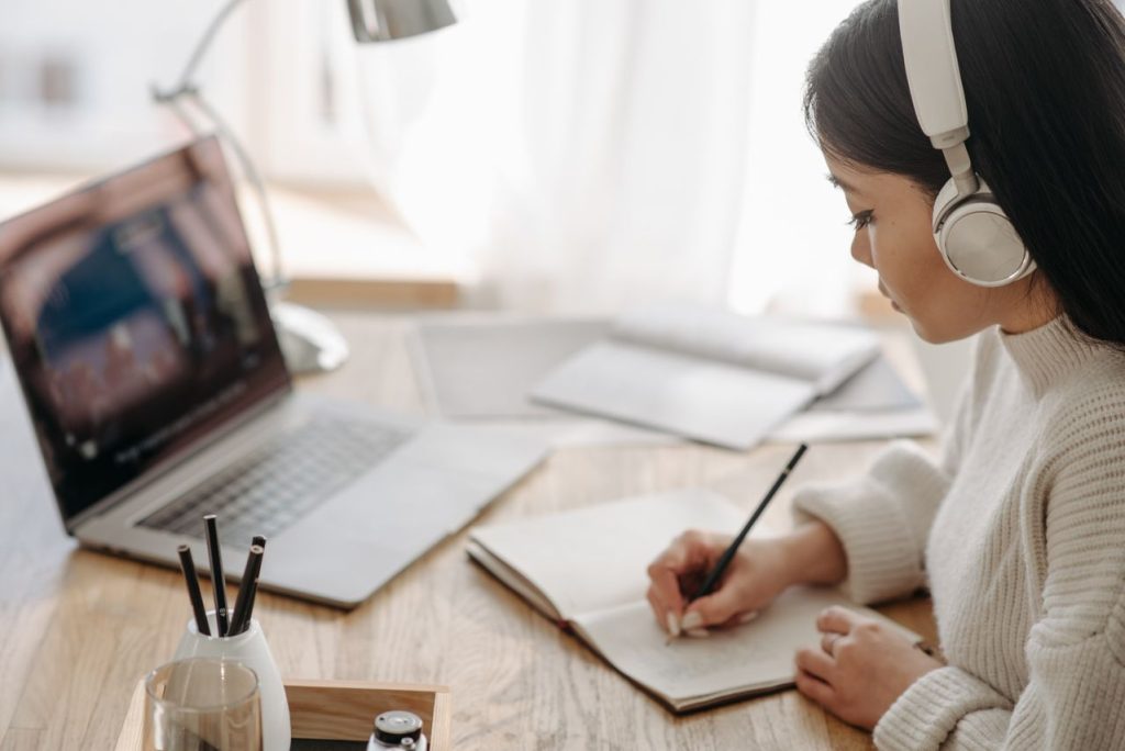 Alumna participando en una formación online con portátil y cuaderno