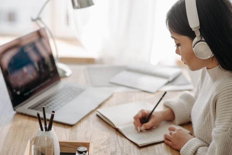 Alumna participando en una formación online con portátil y cuaderno